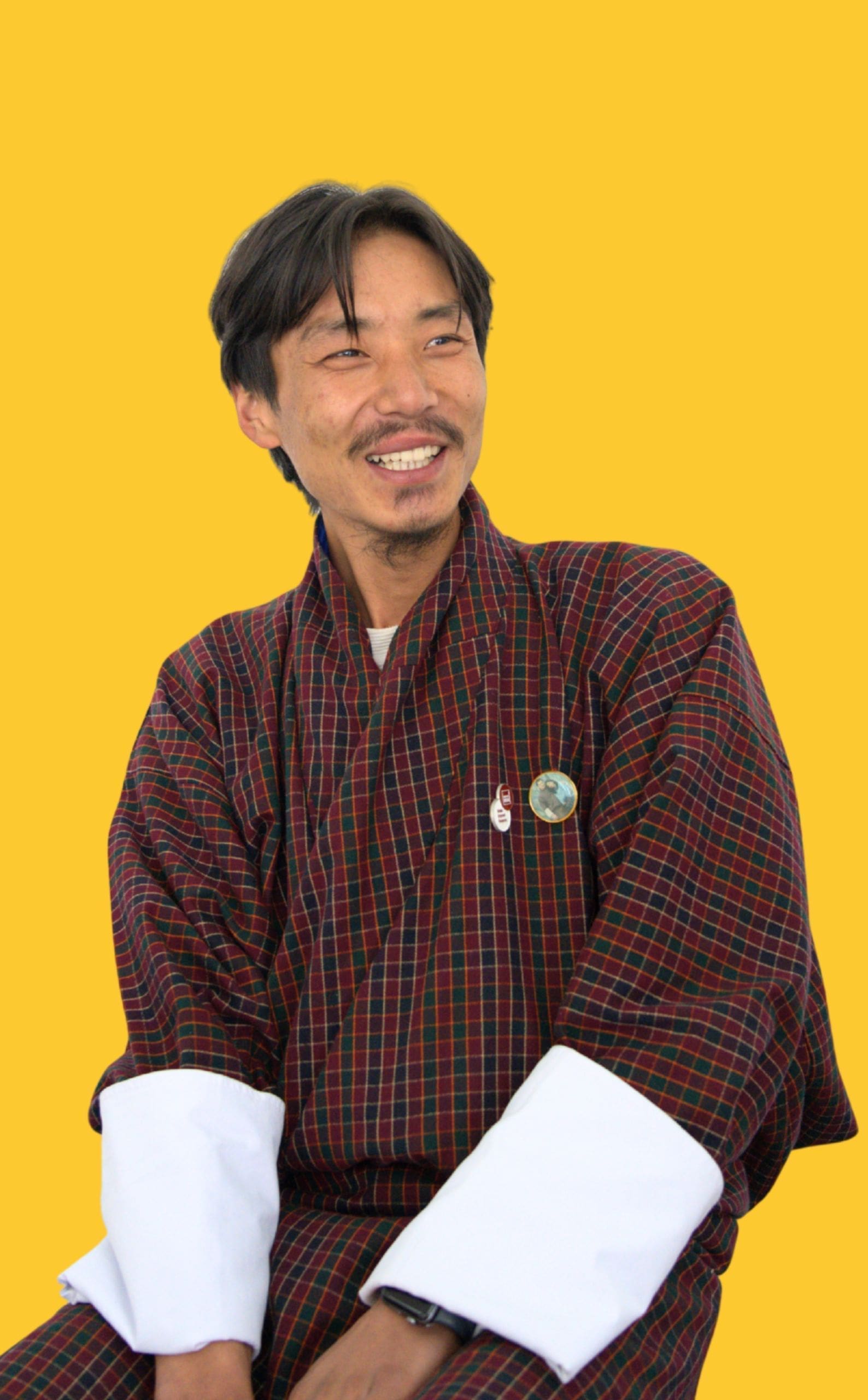 A man sitting and Laughing wear gho is HR & Admin Coordinator of Impact Hub Thimphu