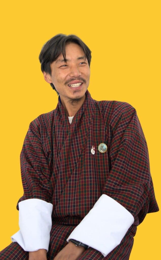 A man sitting and Laughing wear gho is HR & Admin Coordinator of Impact Hub Thimphu